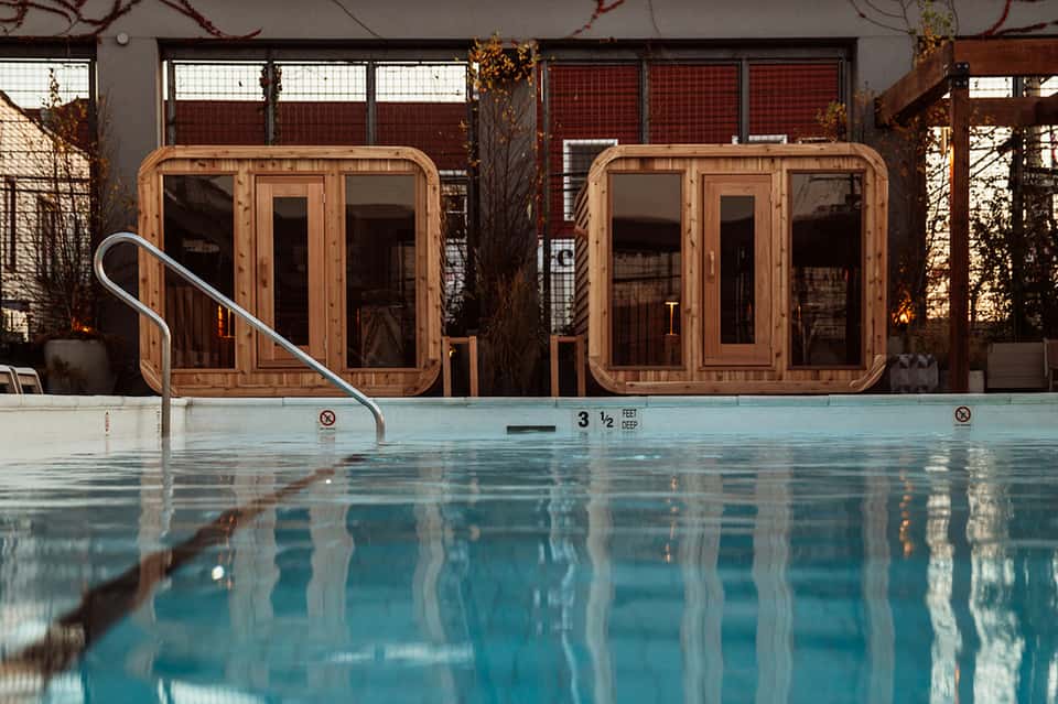 Indoor swimming pool with wooden sauna cabins and stainless steel handrail