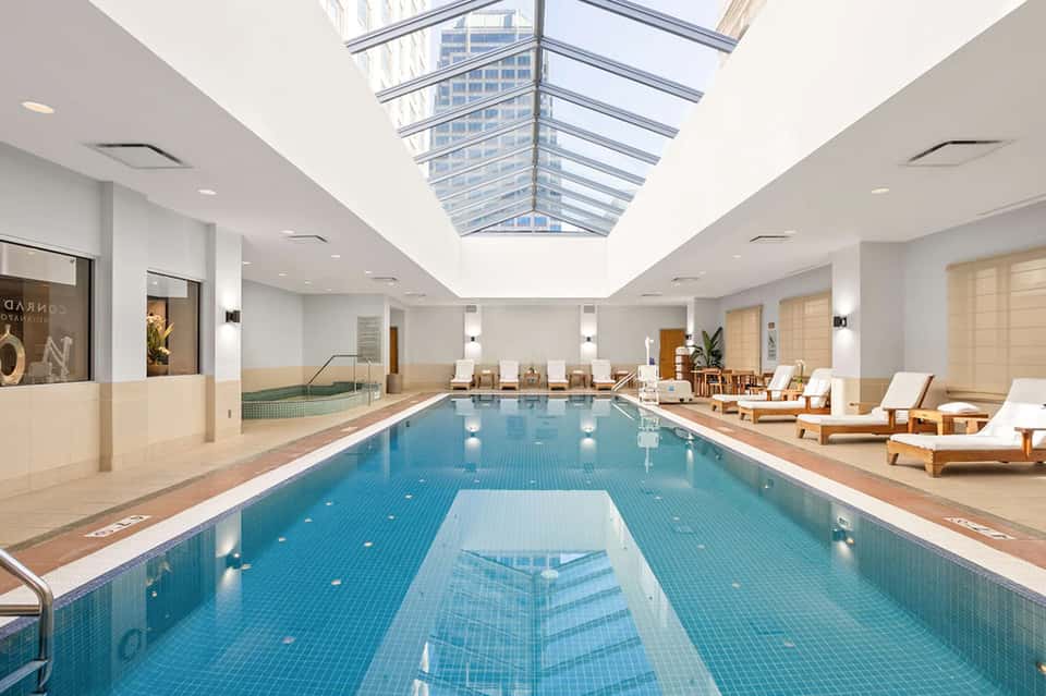 Indoor lap pool under skylight ceiling with lounge chairs and spa facilities