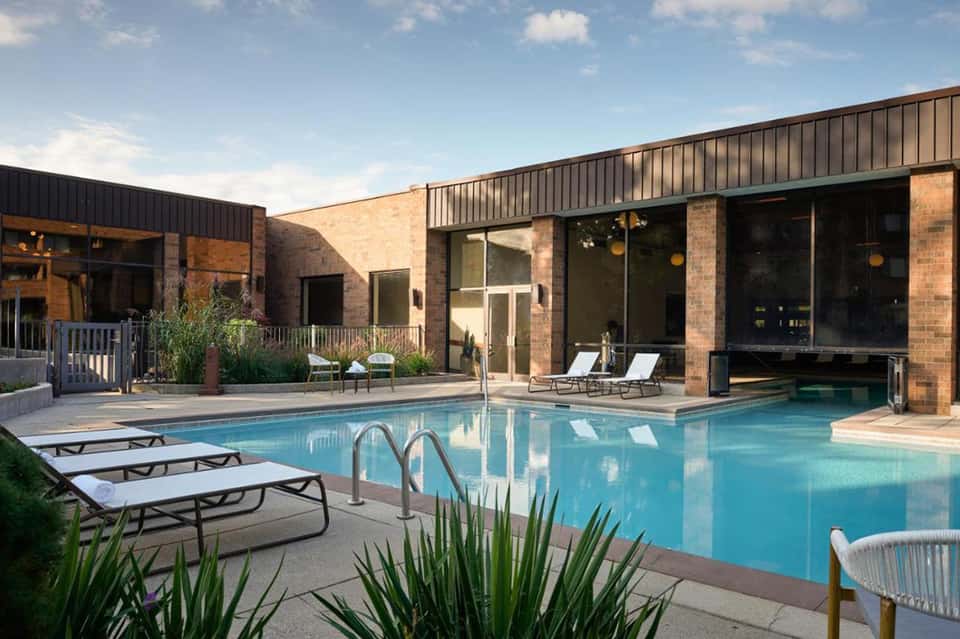 Resort swimming pool with lounge chairs, modern brick building, and clear blue water
