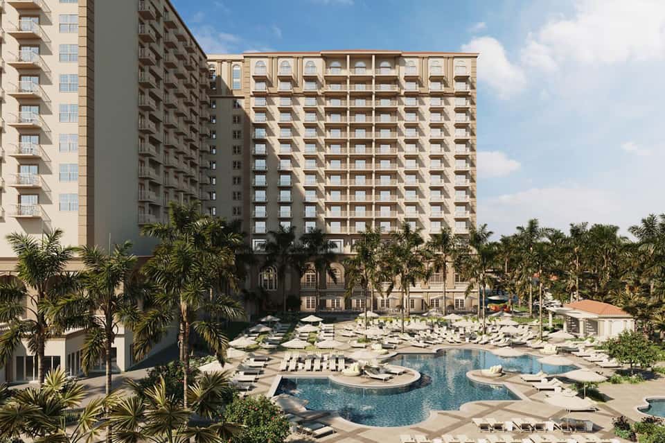 Resort courtyard with lagoon pool, lounge chairs, palm landscaping, and high-rise buildings