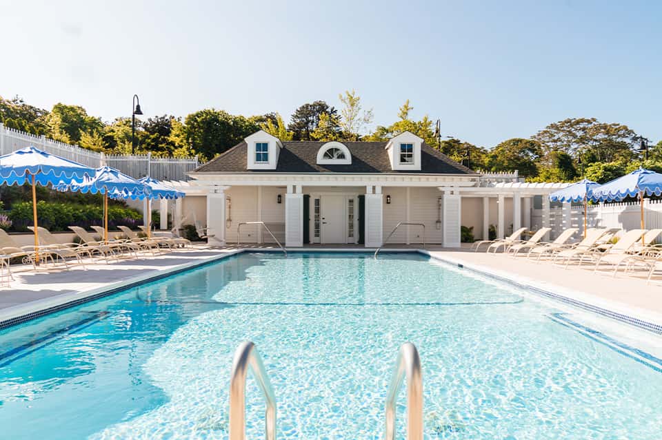 Olympic-style swimming pool with white cabana building and blue umbrellas