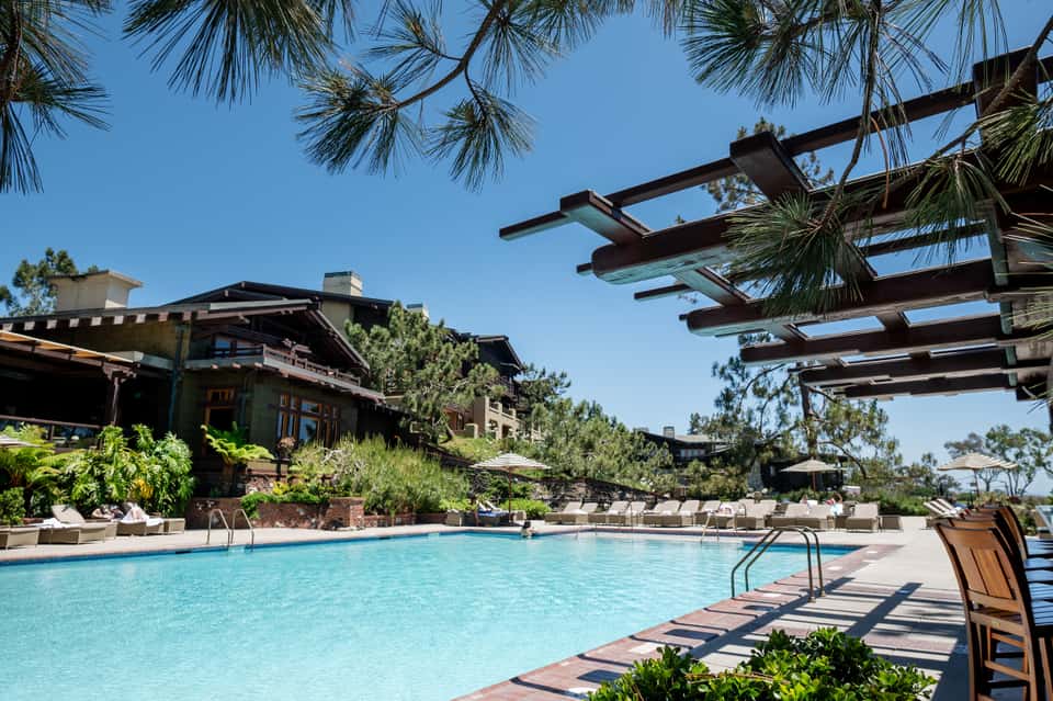 Resort pool with pergolas, loungers, and modern building with landscaped grounds
