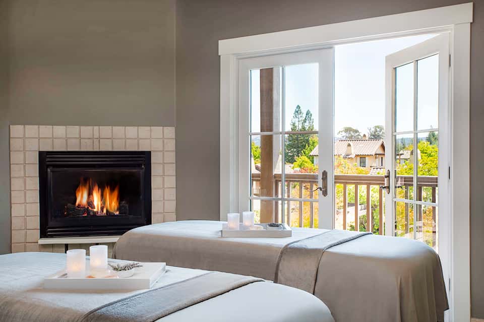 Luxury spa room with fireplace, two massage beds, and ocean view balcony
