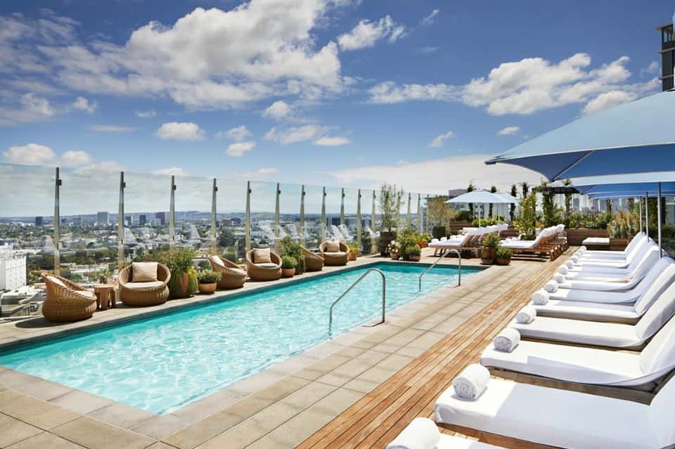 Rooftop pool deck with lounge chairs, umbrellas, and panoramic city skyline views