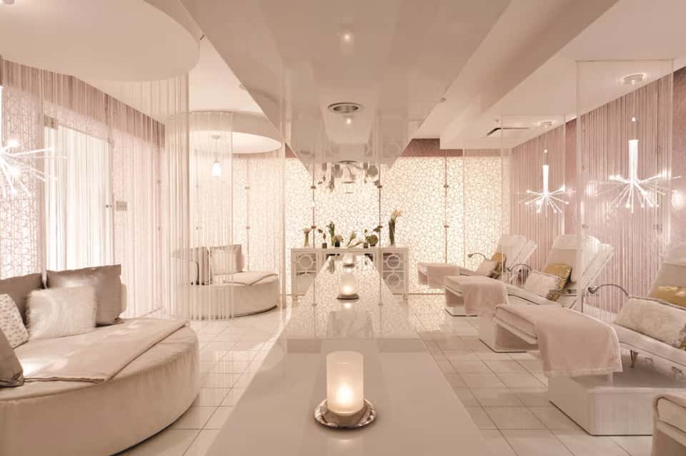 Luxurious spa lounge with pink marble, soft seating, pendant lights, and geometric wall panels