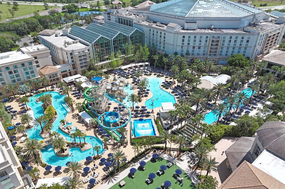 Aerial view of large resort complex with multiple pools, water slides, surrounding hotel buildings