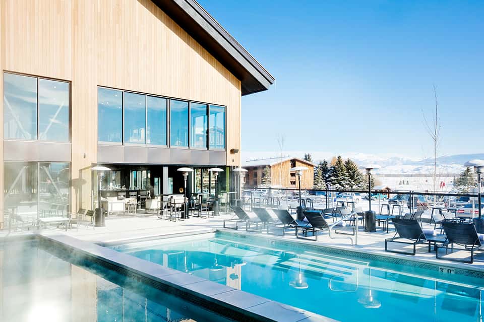 Contemporary hotel pool with heated water and mountain views, modern architecture with large windows