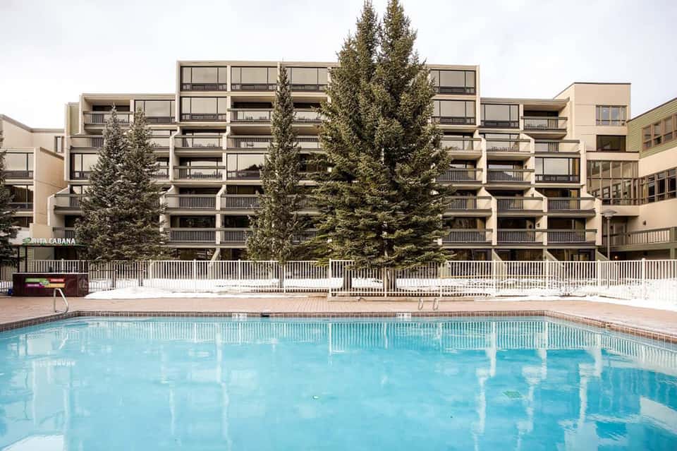 Modern residential building with evergreen trees reflected in swimming pool