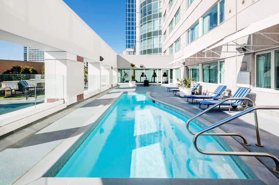 Resort lap pool with blue water, lounge chairs, and surrounding buildings on sunny day