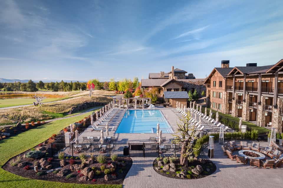 Resort pool with loungers surrounded by manicured grounds and stone buildings with autumn foliage