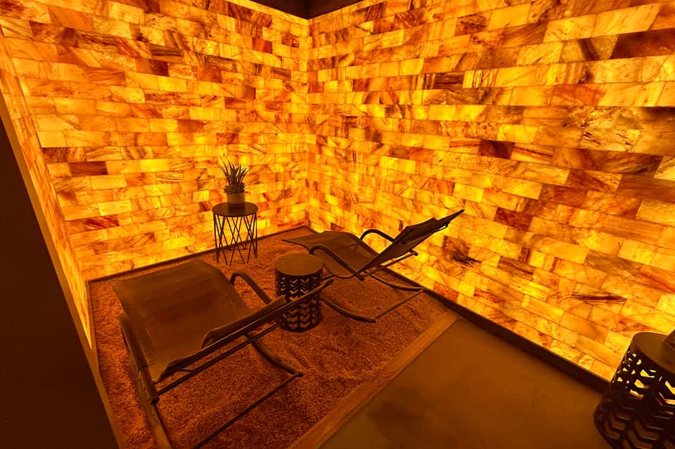 Illuminated salt therapy room with warm amber-glowing brick walls and lounge chairs