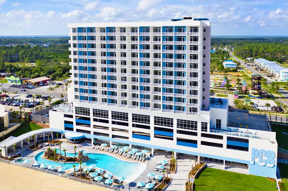 Modern beachfront resort building with blue and white striped parking garage and curved pool deck