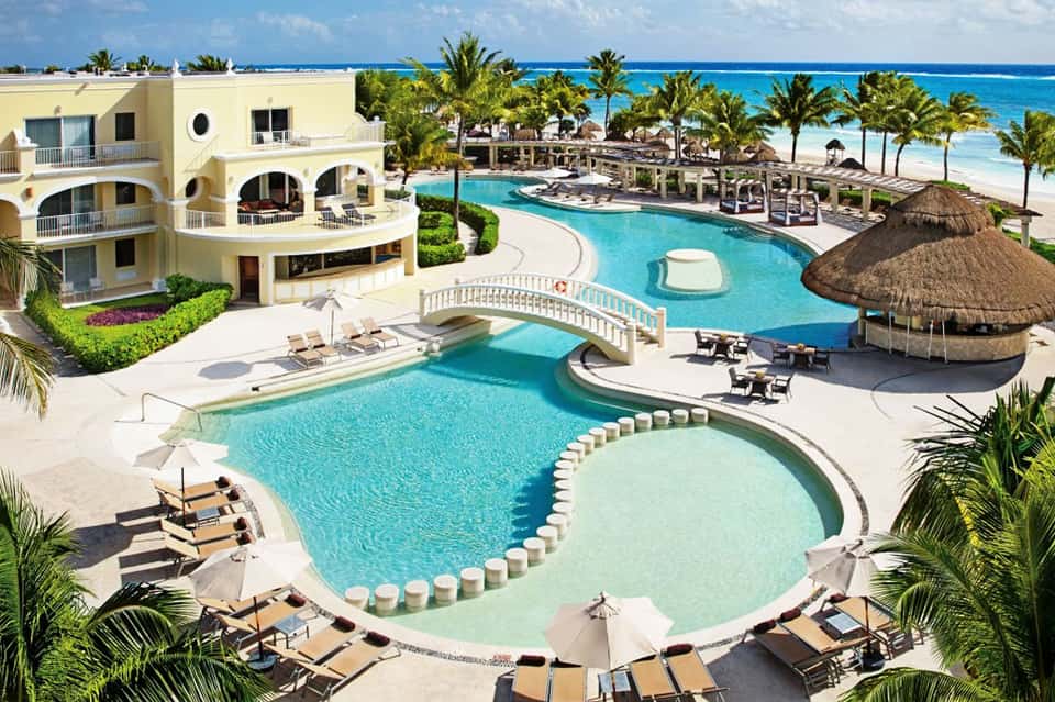 Luxury beachfront resort with curved swimming pools, palm trees, and oceanview architecture