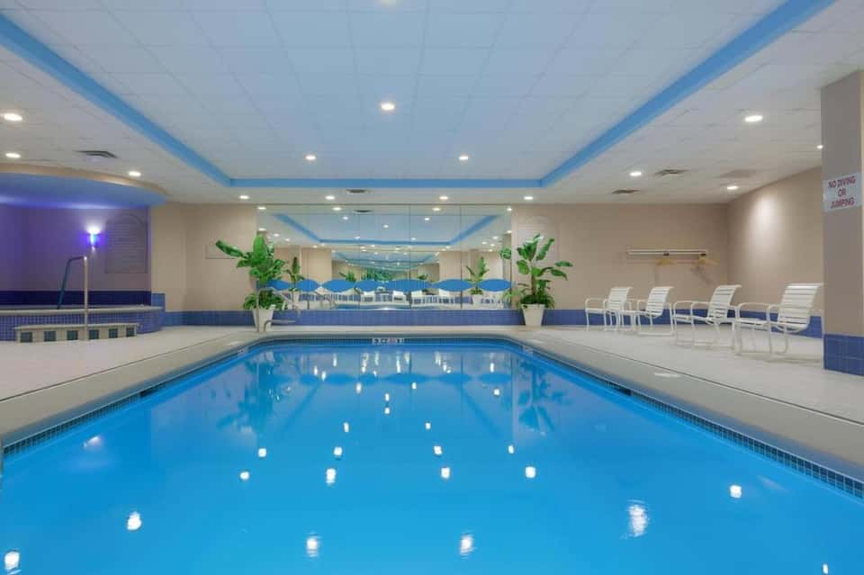 Indoor swimming pool with blue water, white ceiling, lane dividers, and lounge seating area