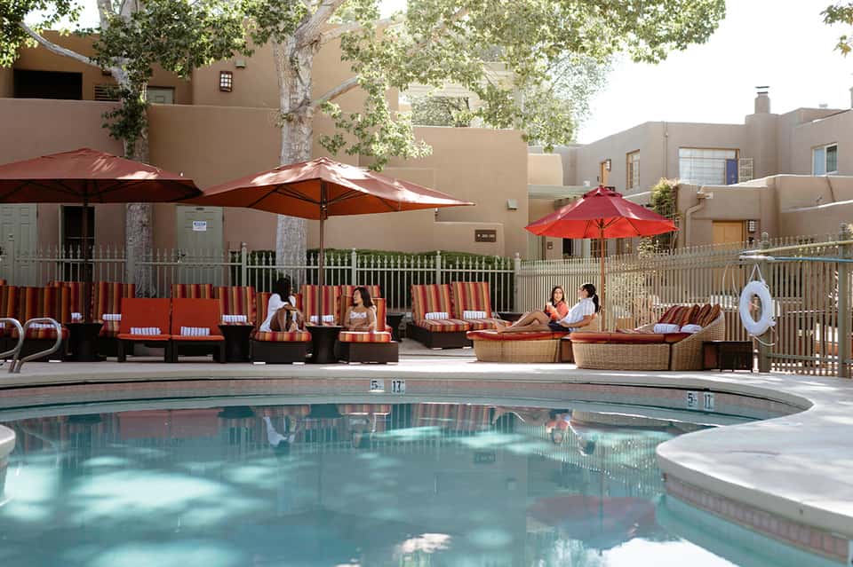 Resort pool area with orange and red striped loungers, umbrellas, and wicker seating