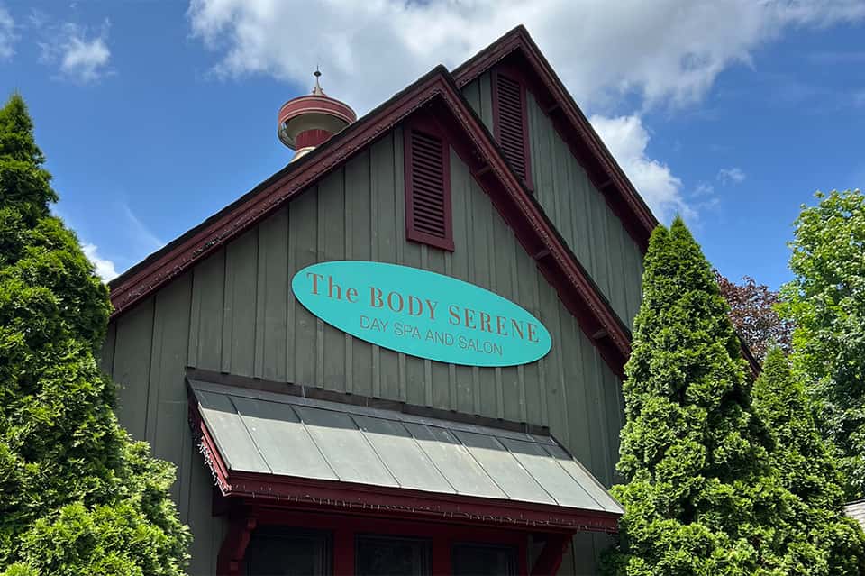 The Body Serene Day Spa and Salon exterior with turquoise sign on green-sided building