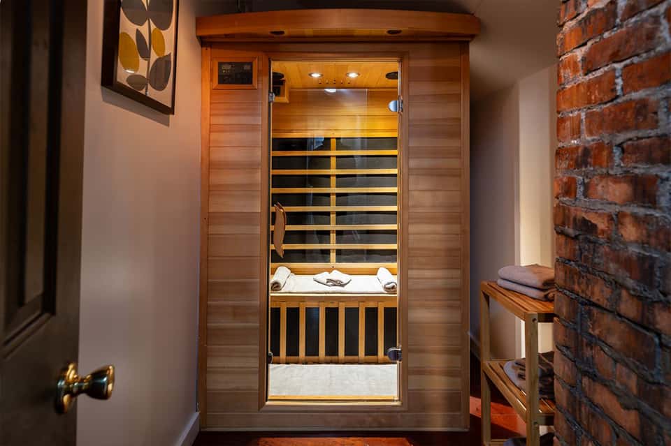 Wooden infrared sauna with glass door and black and tan interior heating panels