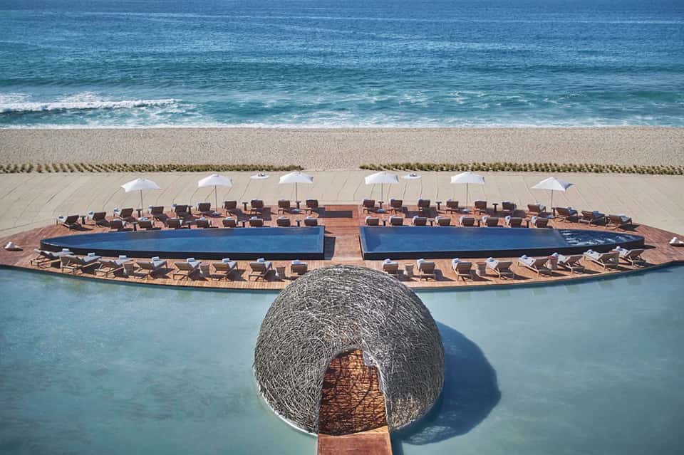 Aerial view of beachfront pool deck with loungers, umbrellas, and ocean waves