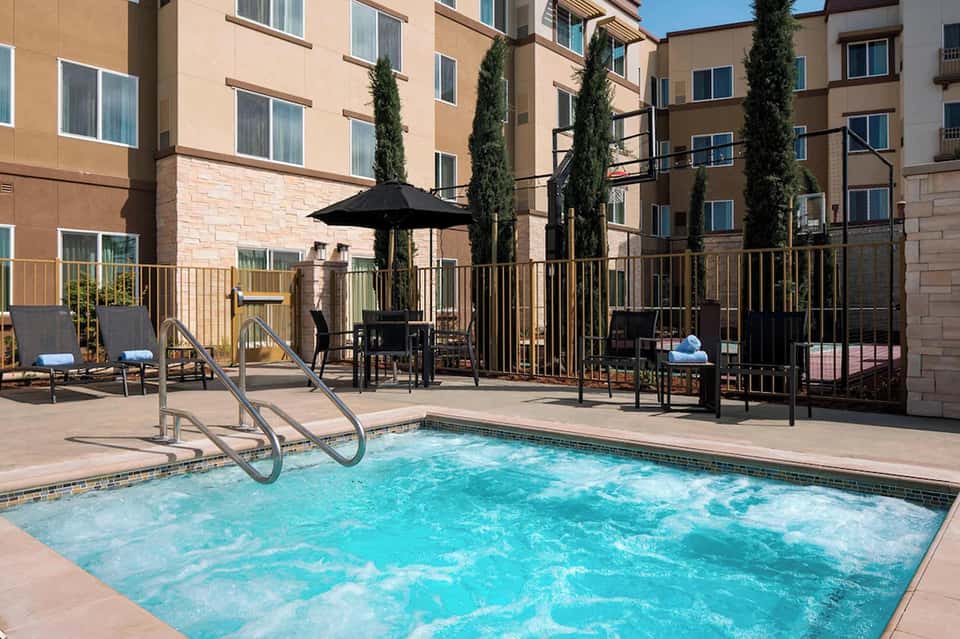 Outdoor swimming pool with lounge chairs, umbrellas, and modern residential building