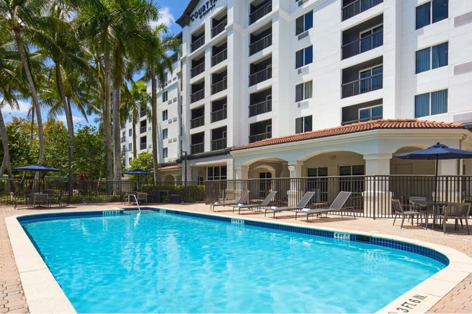 Resort outdoor pool surrounded by palm trees and modern building