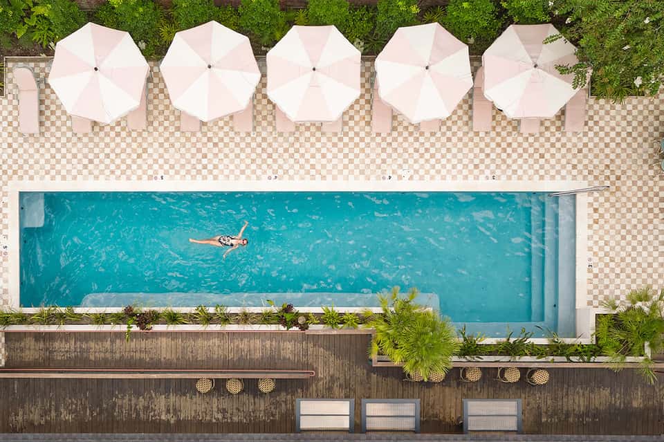 Aerial view of narrow lap pool with white umbrellas and loungers on deck