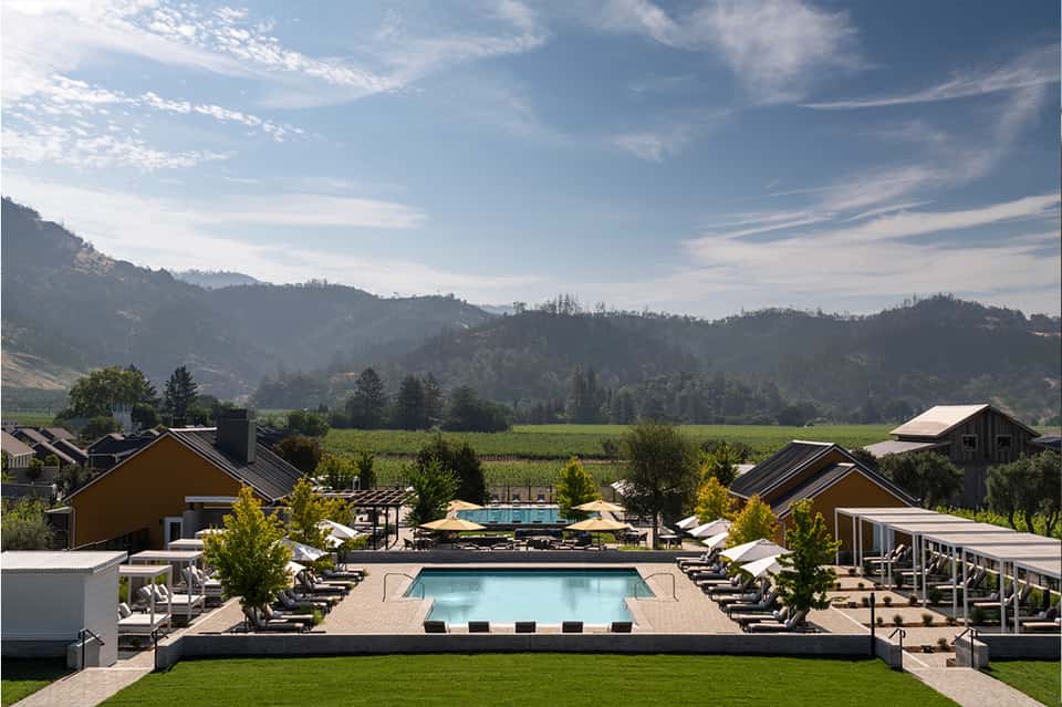 Resort pool nestled in valley with mountains, lounge chairs, and manicured grounds