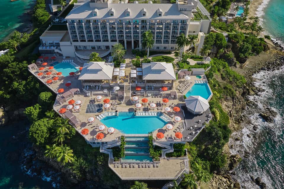 Aerial view of beachfront resort with pools, cabanas, and ocean access