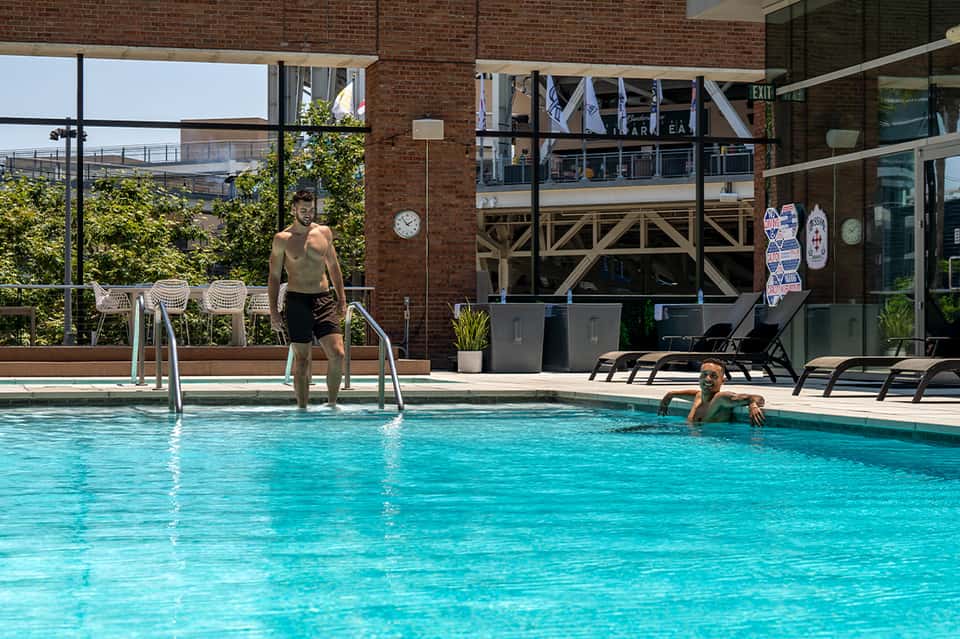 Indoor pool with brick walls, man stepping out and child in water, lounge chairs visible