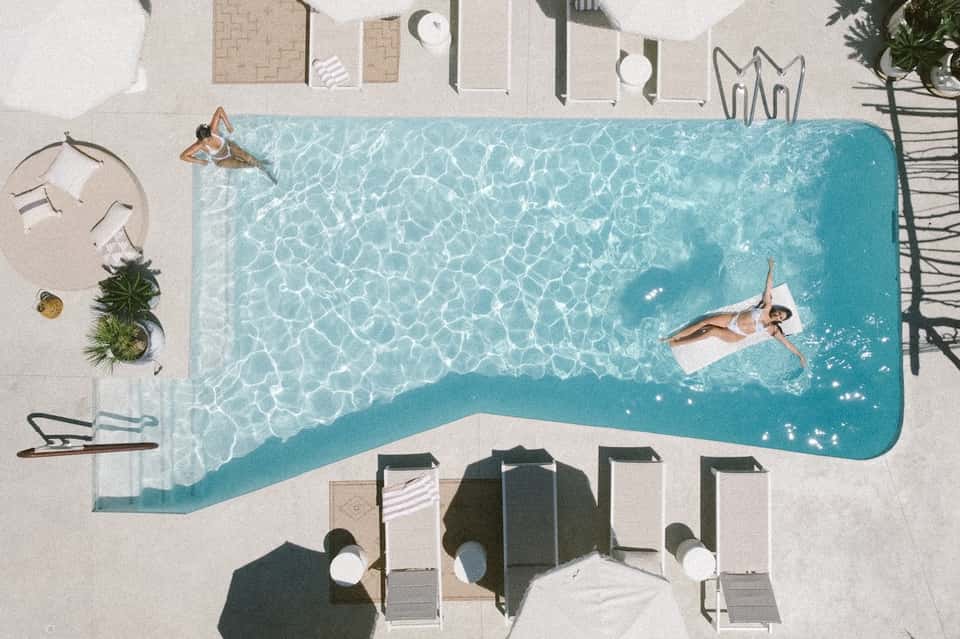 Overhead view of resort pool with guests, lounge chairs, umbrellas, and beach access