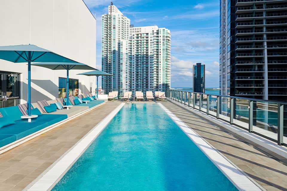 Rooftop infinity pool with turquoise water and lounge chairs overlooking city skyline