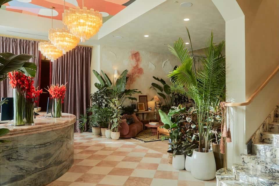 Hotel lobby with round marble reception desk, crystal chandeliers, and tropical plants