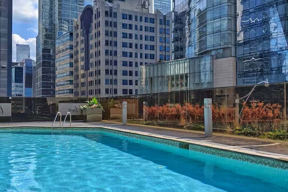 Urban rooftop pool surrounded by downtown skyscrapers with modern glass and steel architecture