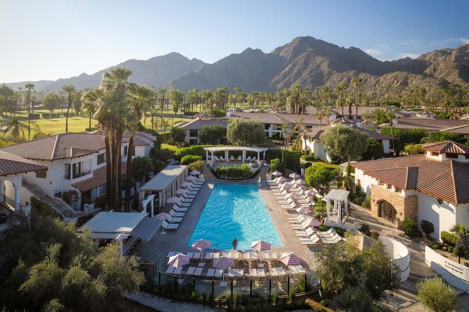 Aerial view of resort pool surrounded by casitas with mountain backdrop and palm trees