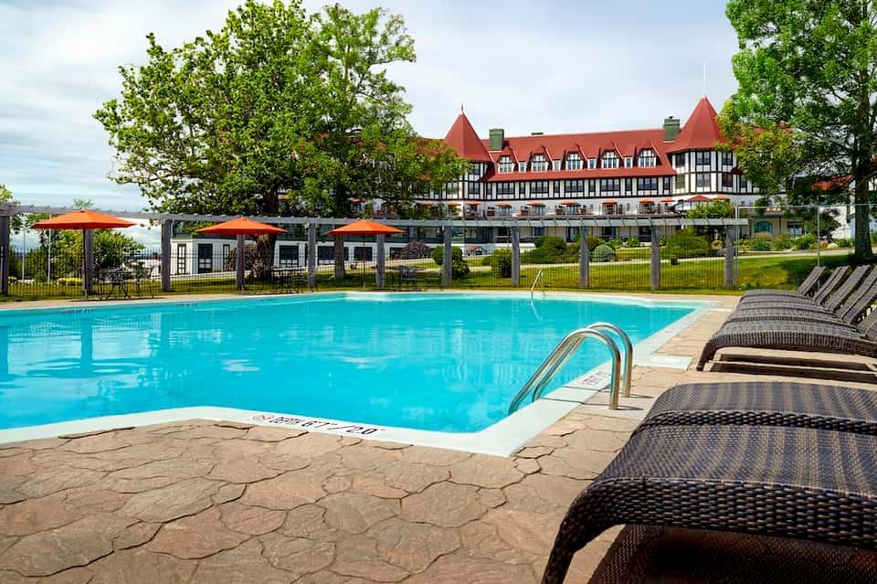 Outdoor swimming pool with lounge chairs, orange umbrellas, and traditional architecture building