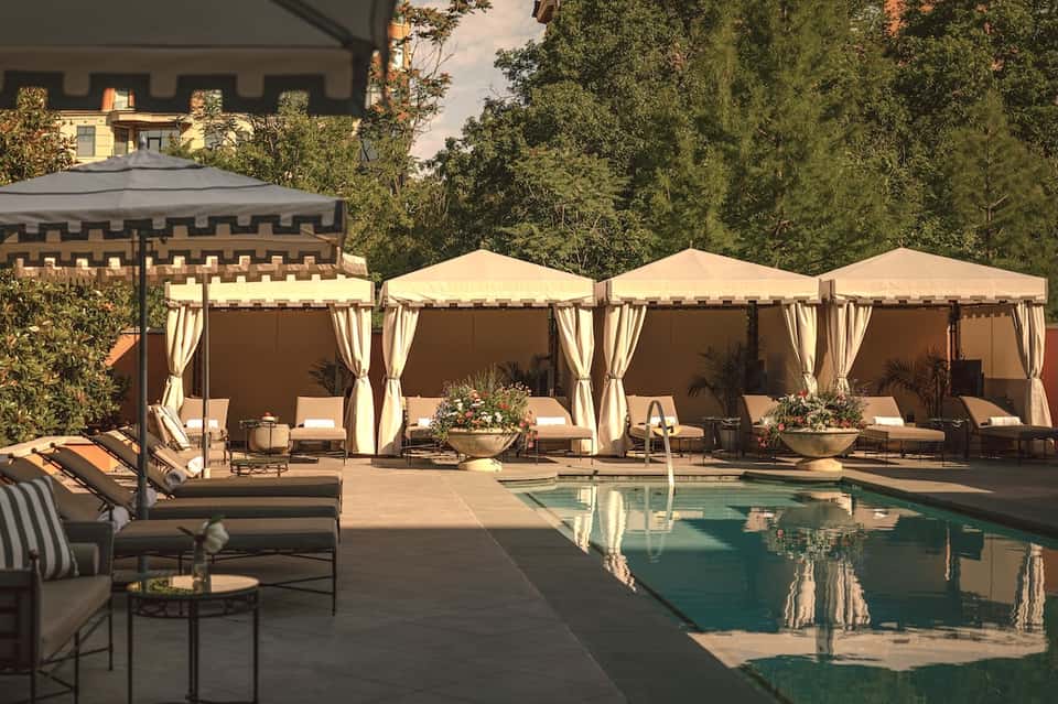Luxury pool deck with cabanas and lounge chairs surrounded by landscaping