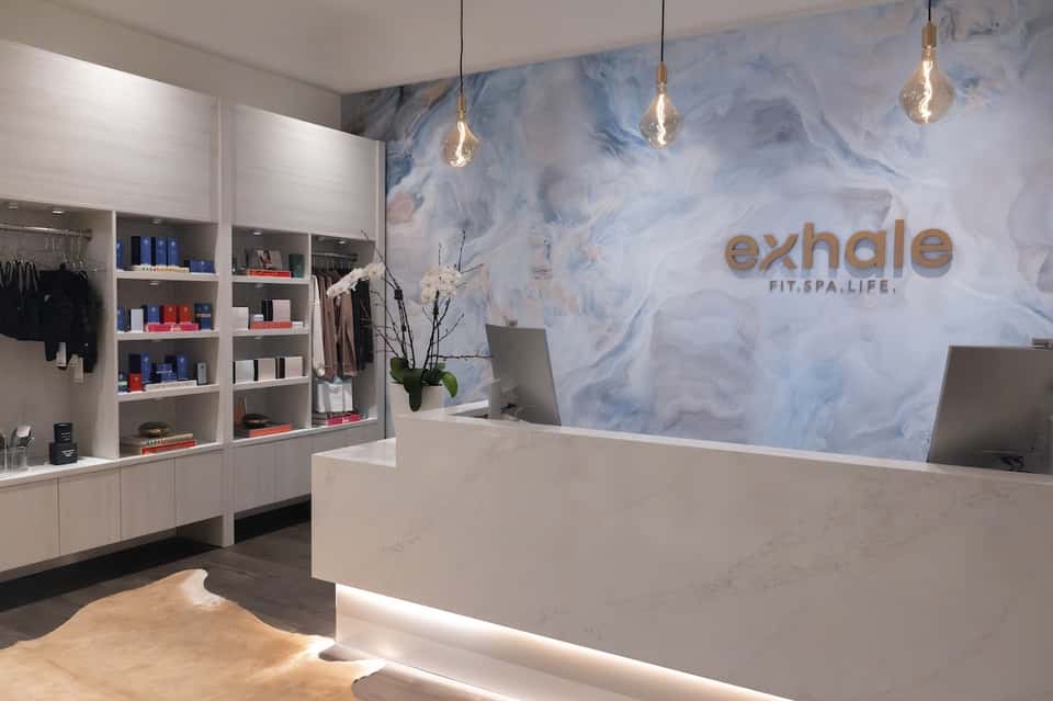 Modern spa reception desk with blue marble wall and product displays