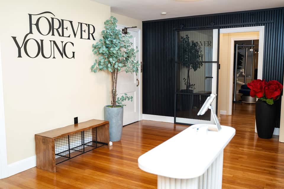 Modern spa entrance with "Forever Young" signage, wooden flooring, and minimalist interior design