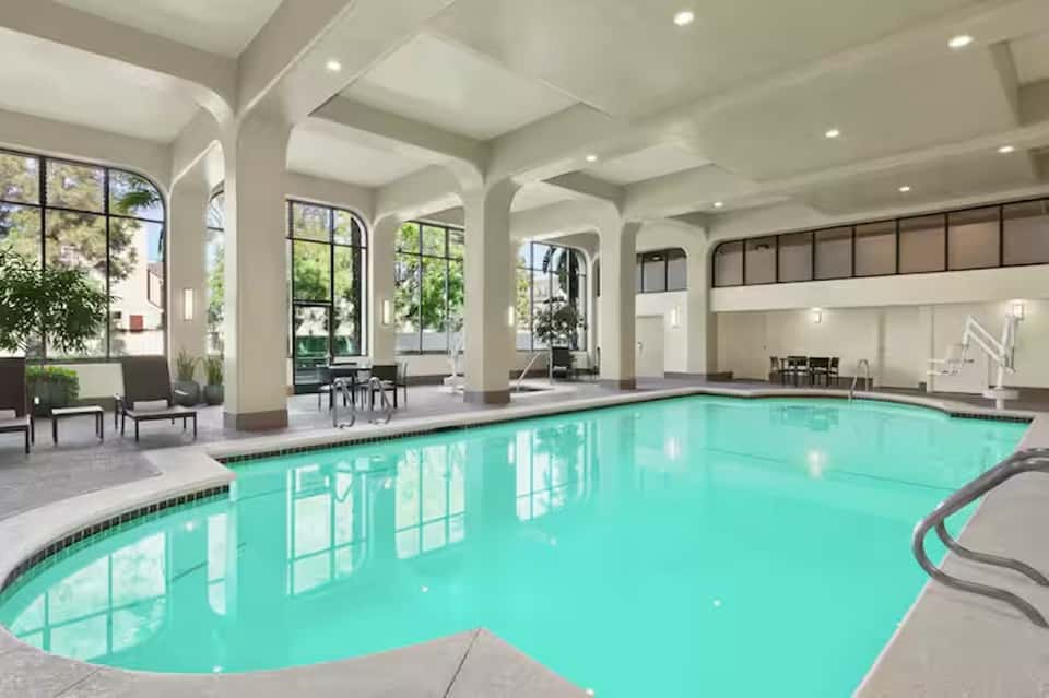Indoor pool with barrel vault ceiling, arched columns, and large windows in contemporary hotel atrium