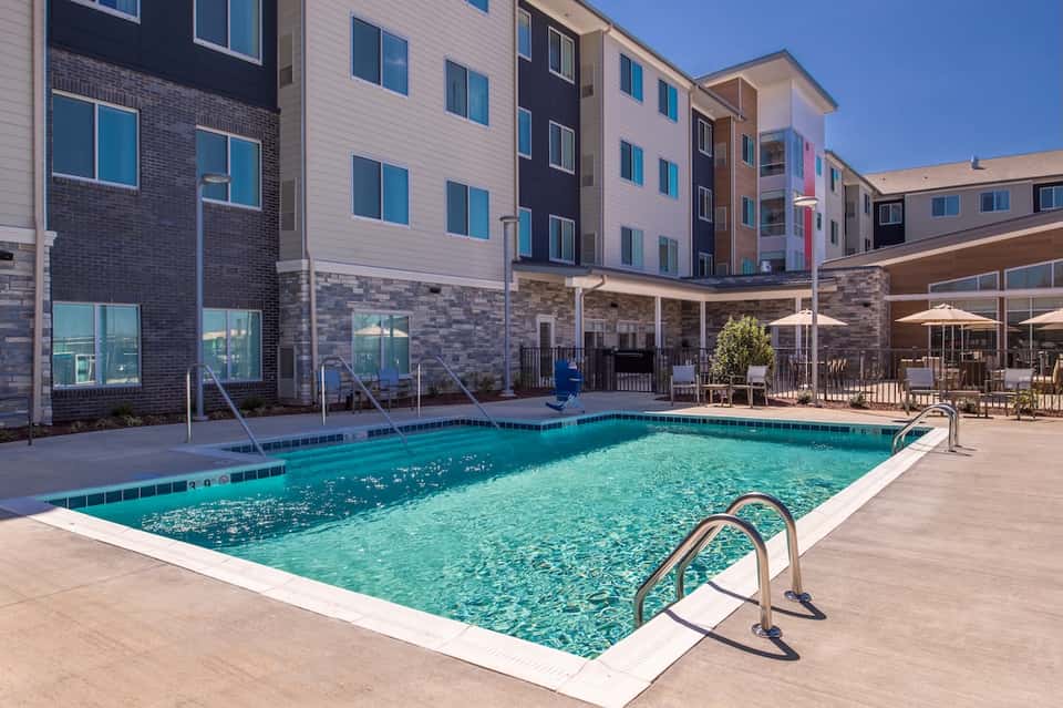 Outdoor swimming pool at residential complex with lounge chairs and covered seating area