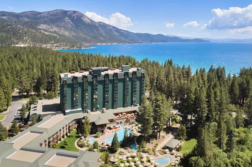 Mountain resort overlooking pristine blue lake, surrounded by dense forest landscape