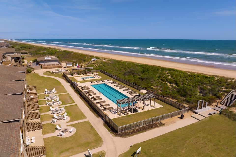 Beachfront resort with pool overlooking pristine sandy beach, ocean, and coastal dune landscape