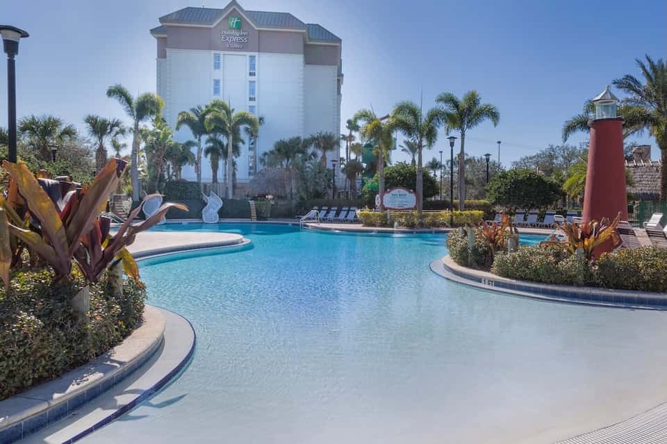 Resort lazy river pool with palm trees, tropical landscaping, and hotel tower