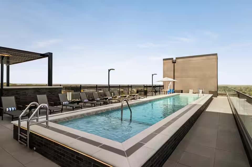 Rooftop pool with lounge chairs, umbrellas, and scenic landscape views on clear day