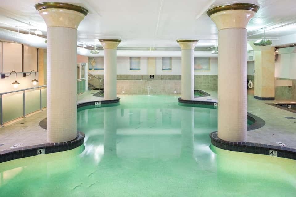 Indoor thermal pool with mineral water, decorative columns, and spa ambiance