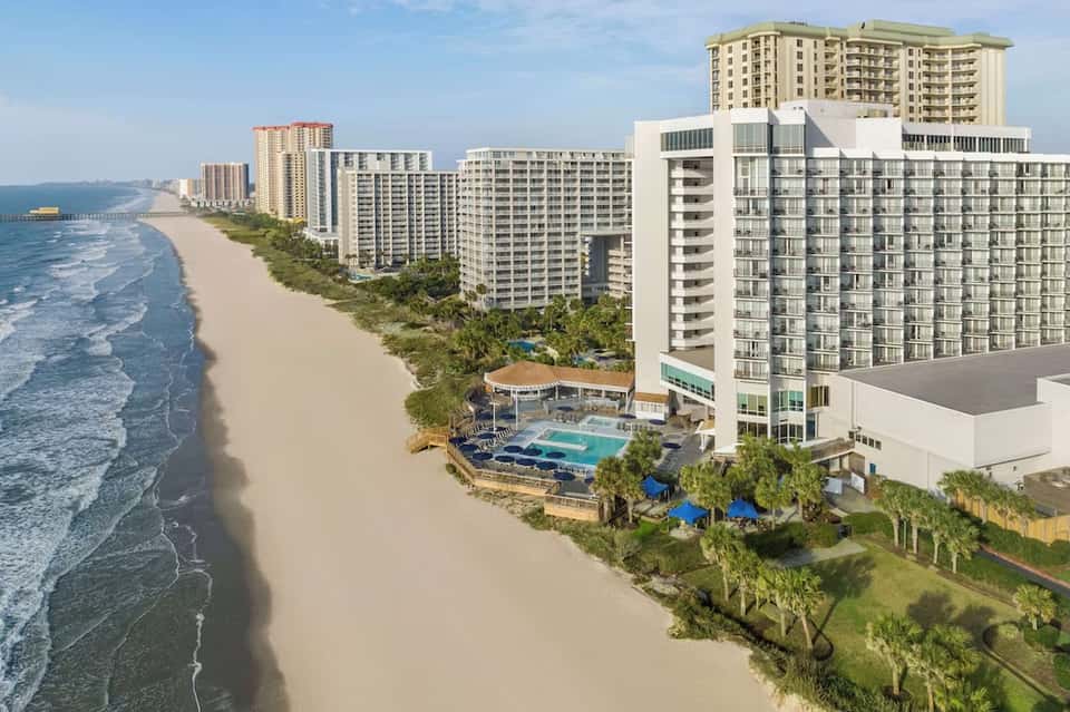 Beachfront resort property with multiple towers and pool overlooking sandy beach and ocean