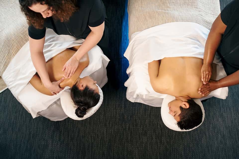 Two therapists performing spa massages on clients lying on massage tables