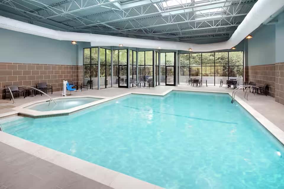 Indoor heated swimming pool with skylights, spa tub, and patio door access