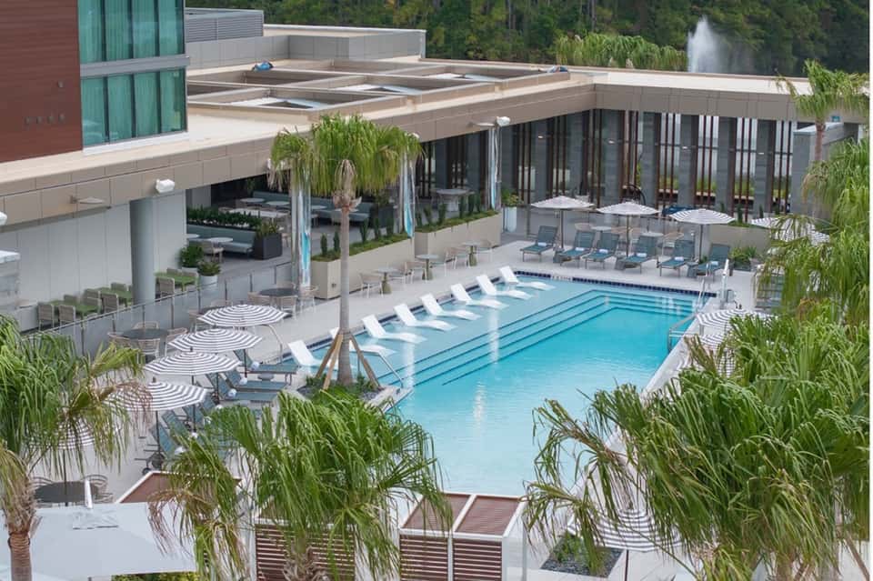 Luxurious resort pool with lap lanes, lounge chairs, and modern buildings