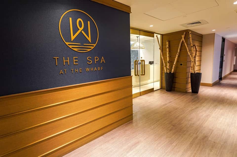 Spa entrance with gold logo sign "The Spa at the Wharf" and wooden accent wall