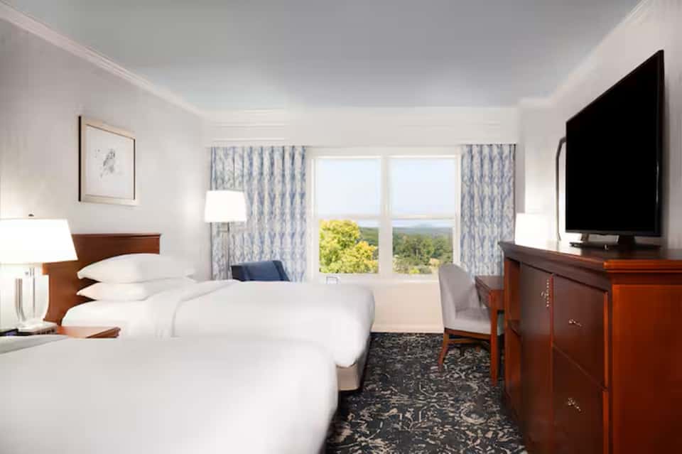 Hotel room with two queen beds, mountain view windows, and traditional wood furnishings